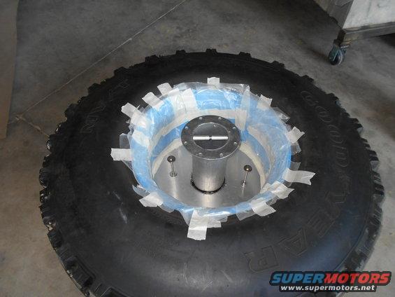Tire with a metal hub adapter taped in place with blue and white tape