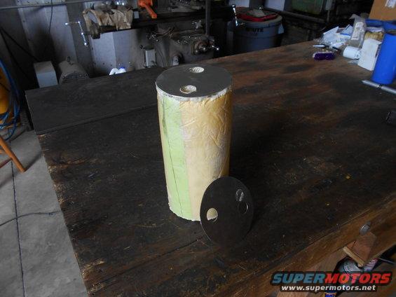 cylindrical part with two metal caps, one on top and one beside it, on a workbench