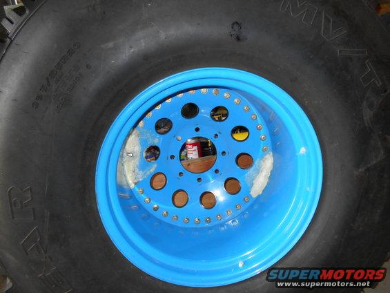 Blue beadlock wheel with large tire, showing lug nut holes and tire sidewall text