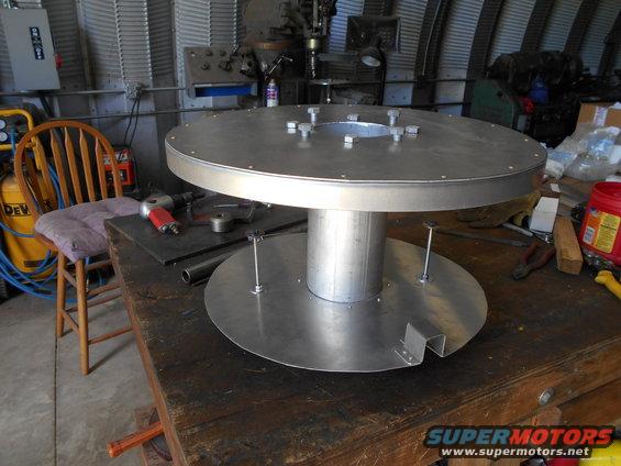 Metal spool with bolts on a workbench, showing a circular base and top
