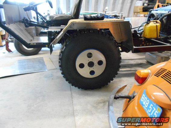 Custom vehicle with large tires next to an orange VW Beetle with license plate BQB 575