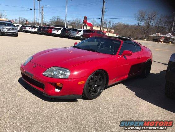 Red sports car with black wheels parked in a lot