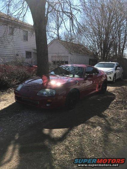 Red Toyota Supra parked next to a white sedan in a yard