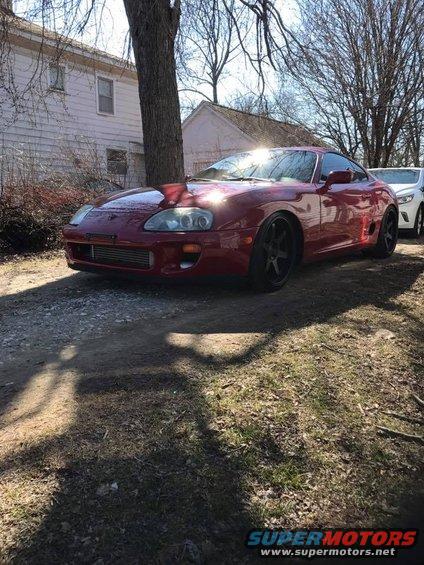 Red sports car parked outside a house, another white car behind it