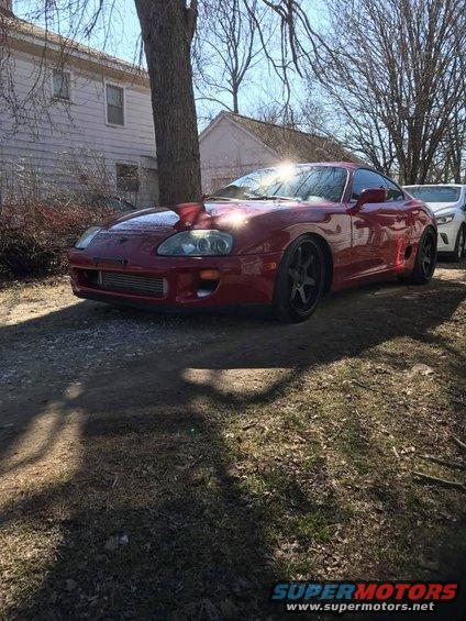 Red Toyota Supra with aftermarket wheels and intercooler visible