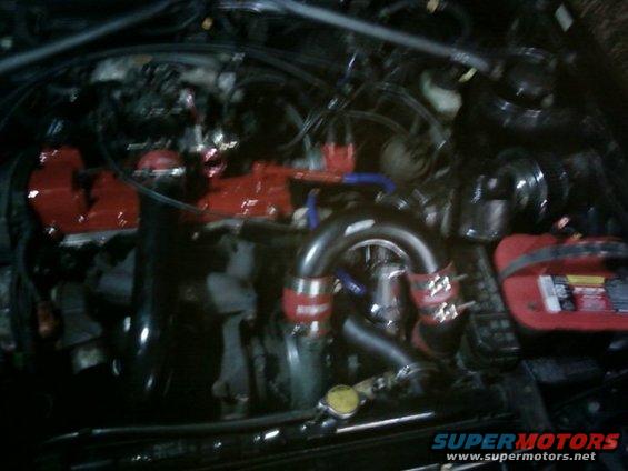 Engine bay with red valve covers and turbo piping
