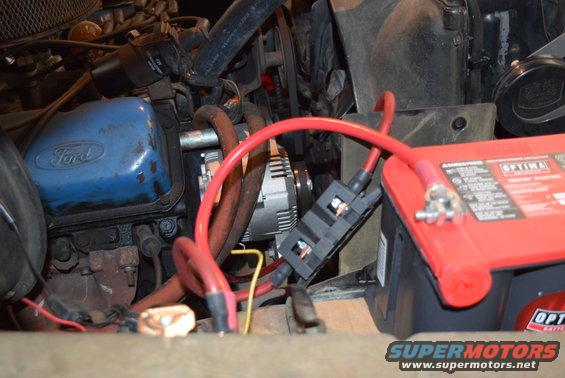 Engine bay with blue Ford valve cover, red Optima battery, and alternator