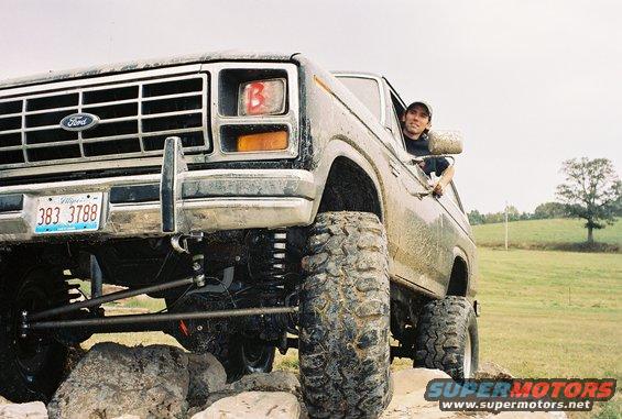 Ford Bronco with large tires on rocks, driver looking out window