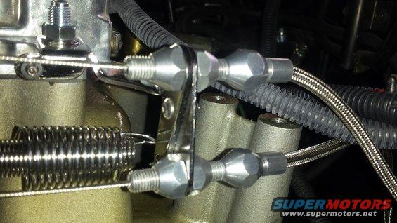 Close-up of throttle linkage connected to a carburetor with a large spring