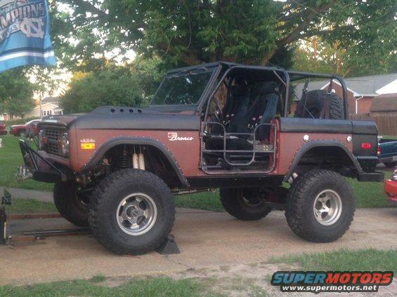 Brown Ford Bronco with roll cage and off-road tires, seen from the front-right