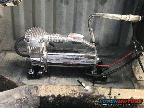 Chrome air compressor with silver braided hose mounted in vehicle bed