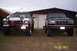 1995 Ford Bronco - Two Ford trucks are parked in front of a garage, one is a black Bronco and the other is a white truck.