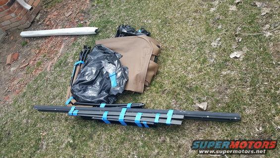 tent poles and fabric bundled with blue tape on grass