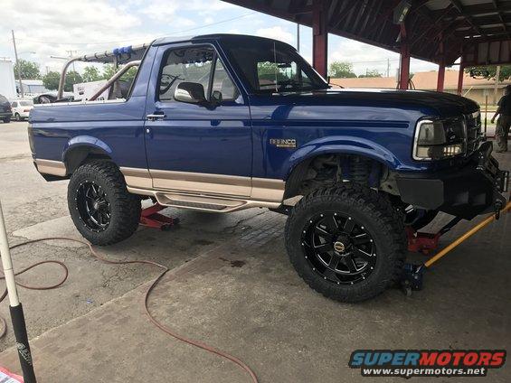 Blue 1996 Ford Bronco with custom wheels and tires on jacks