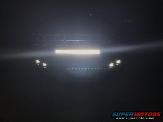 Front view of a dark 1992 Ford Bronco with aftermarket light bars mounted on the grille and bumper