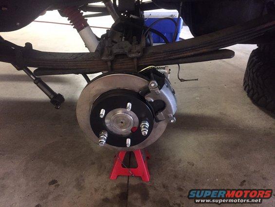 rear brake rotor and caliper assembly on a red jack stand