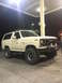 1981 Ford Bronco - This lifted Ford Bronco is parked under a gas station canopy at night, illuminated by overhead lights.