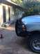 2004 Ford F-150 - A truck is parked in front of a house with a chrome bumper lying on the ground nearby.