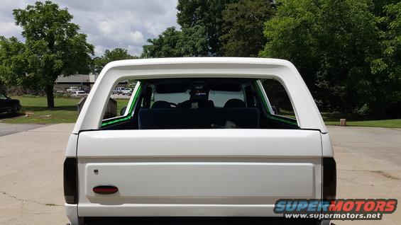 White Ford Bronco rear view. Tinted taillights, aftermarket green trim around rear window