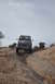 1991 Ford Bronco - A dark SUV with a pop-up camper top navigates a challenging rocky terrain under an overcast sky.