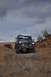 1991 Ford Bronco - A Ford Bronco navigates a rocky desert landscape, with another off-road vehicle in the distance under a cloudy sky.