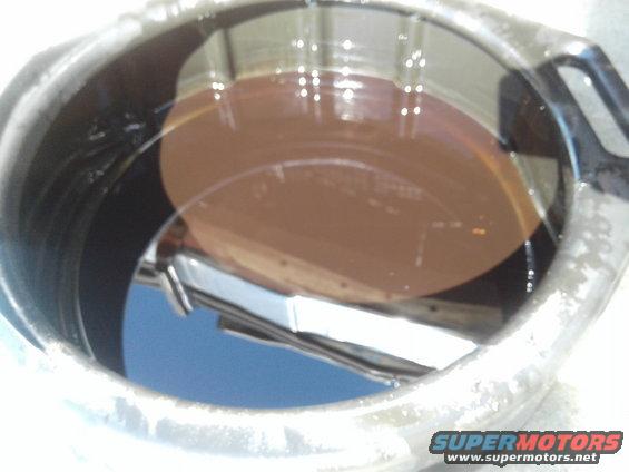 Oil filter housing with brown oil and reflection of blue sky