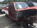 1988 Ford Bronco - This red and white pickup truck, likely from the late 1980s, is seen in a junkyard with its front end heavily damaged and removed.