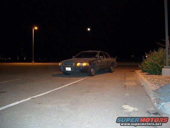 Dark 2001 Ford Crown Victoria parked at night, front-left view, with a full moon overhead
