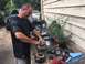 1988 Ford Bronco - Man repairs car alternator parts on a workbench outdoors, with a black Ford truck visible.