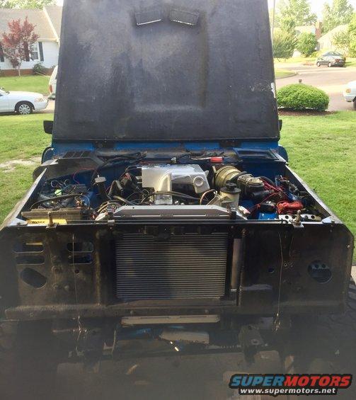 Blue vehicle engine bay with hood open, showing engine and radiator