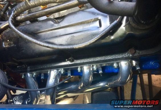 Close-up of chrome exhaust headers and spark plugs on an engine