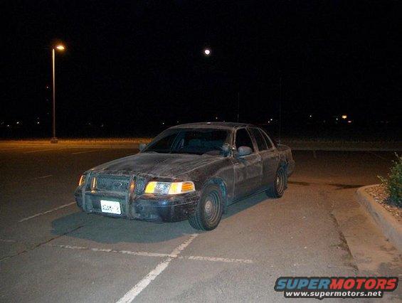 Dark 2001 Ford Crown Victoria with push bar parked at night