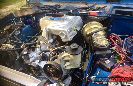 Engine bay with blue paint, silver intake manifold, and brass brake booster