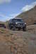 1991 Ford Bronco - Two off-road vehicles navigate a challenging rocky terrain under a partly cloudy sky.