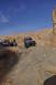 1991 Ford Bronco - Jeep Wrangler navigates a steep rocky incline in Moab, with a Ford Bronco and another SUV waiting on the trail.