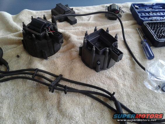 distributor caps and spark plug wires laid out on a towel with a toolbox and screwdriver