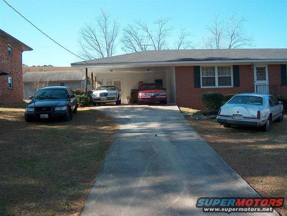 2001 Ford Crown Victoria, white Lincoln Town Car, and red sedan parked in driveway and yard