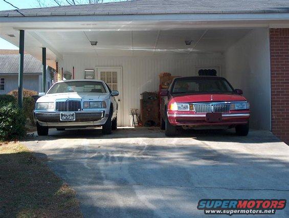 White sedan and red sedan parked side-by-side in a carport