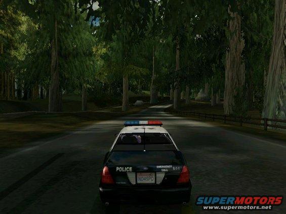 Police car from behind, black with light bar, on a tree-lined road