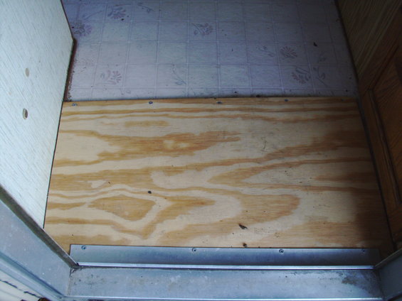 Wooden floor panel with metal threshold strip