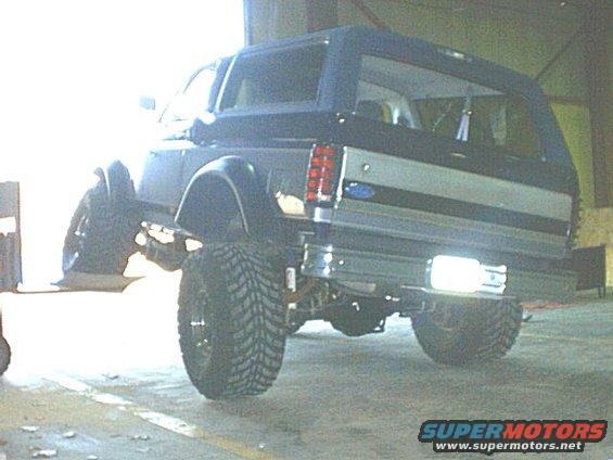 Dark blue Ford Bronco with lifted suspension and large tires, viewed from the rear