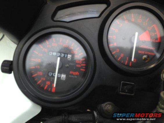 Motorcycle dashboard with speedometer showing 83312 miles and tachometer