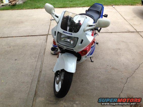 Front view of a white, red, and blue 1989 Honda CBR600F motorcycle parked on a concrete driveway