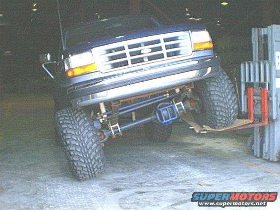 1995 Ford Bronco front end lifted by forklift, showing custom suspension