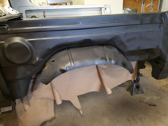 Close-up of a vehicle's rear wheel well interior with brown paper lining