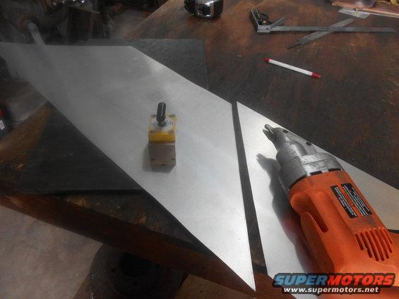 Metal sheets on a workbench with a yellow magnetic base and an orange power tool