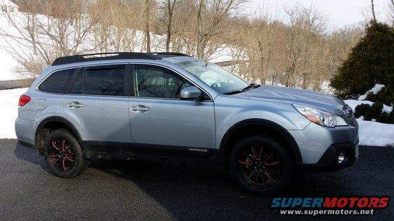 Silver 2014 Subaru Outback wagon parked outside in winter, showing side profile and front quarter. It has black trim and red-accented wheels