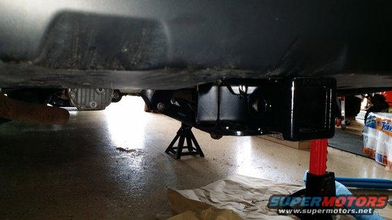 Trailer hitch receiver mounted on a vehicle's undercarriage, supported by jack stands