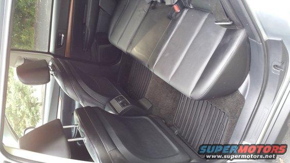 Back seats and floor mats inside a car. Some text visible on floor mats