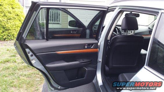 Silver Subaru Outback interior with open rear door, black leather seats, and wood trim